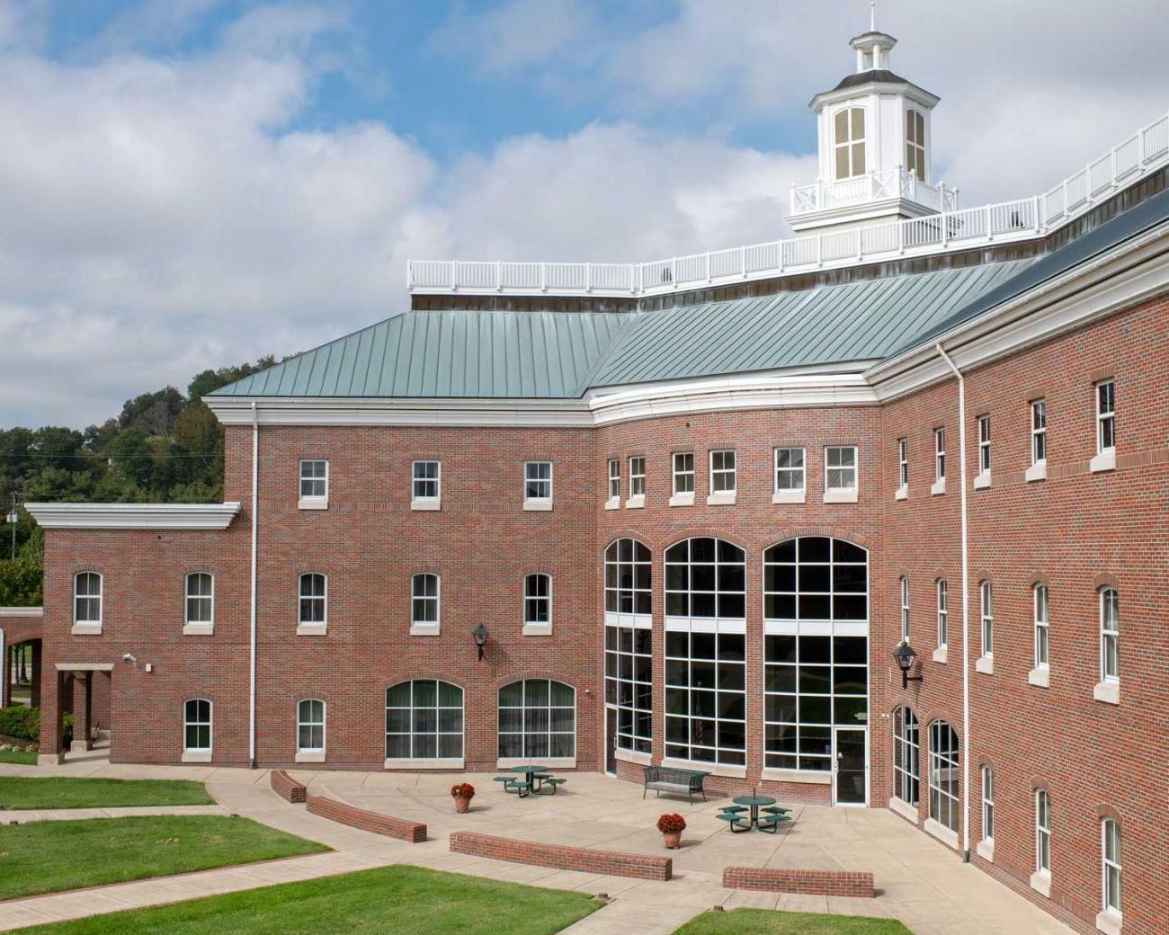 View of a large brick building with a green roof and arched windows