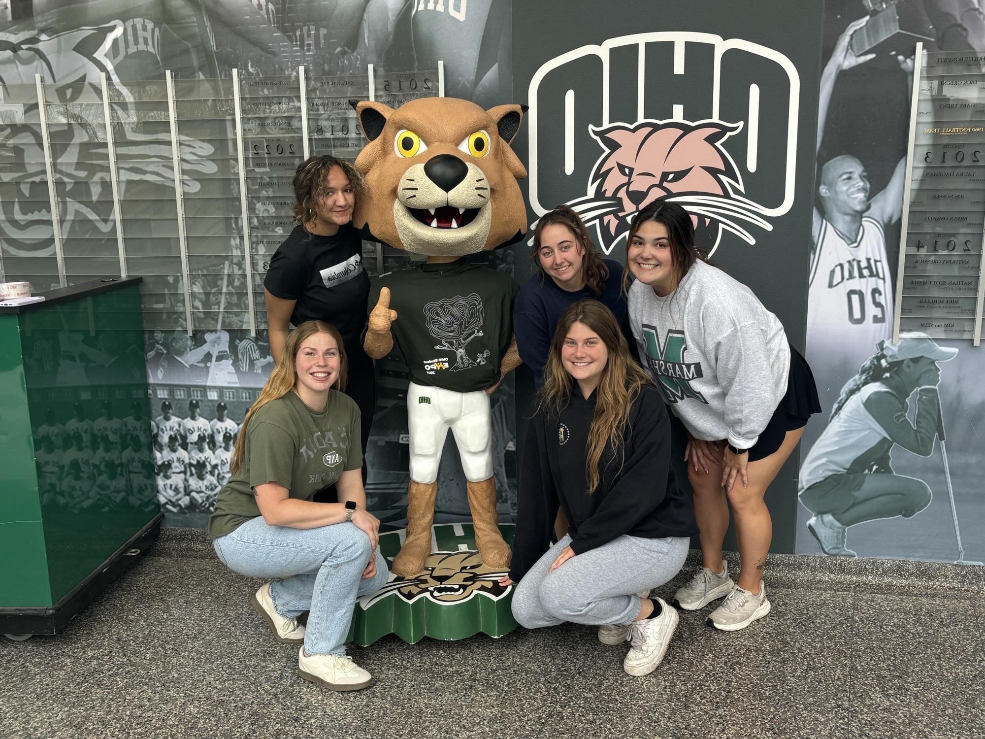 A group of students with a statue of Rufus the Bobcat